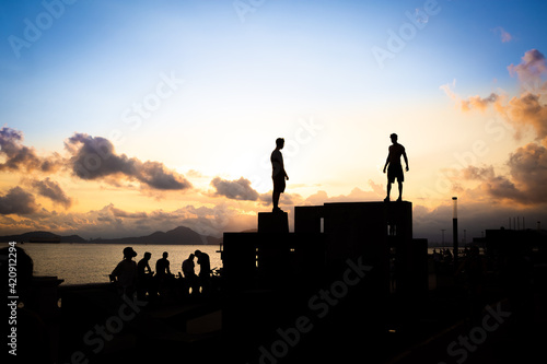Silhouettes of boys practicing parkour during sunset in Santos