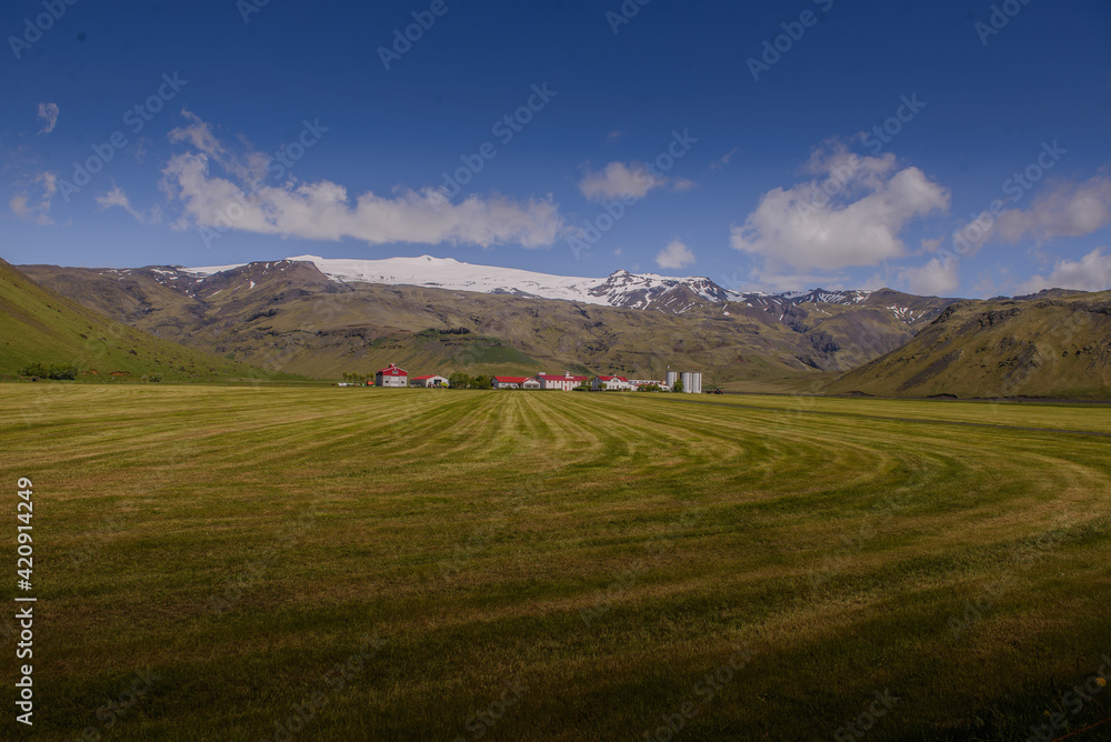 Landscape with distant row of houses and ice cap, Eyjafjallajökull, Iceland Landscape with distant row of houses and ice cap, Eyjafjallajökull, Iceland