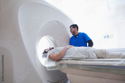Young male radiographer operating CT scanner in radiology department