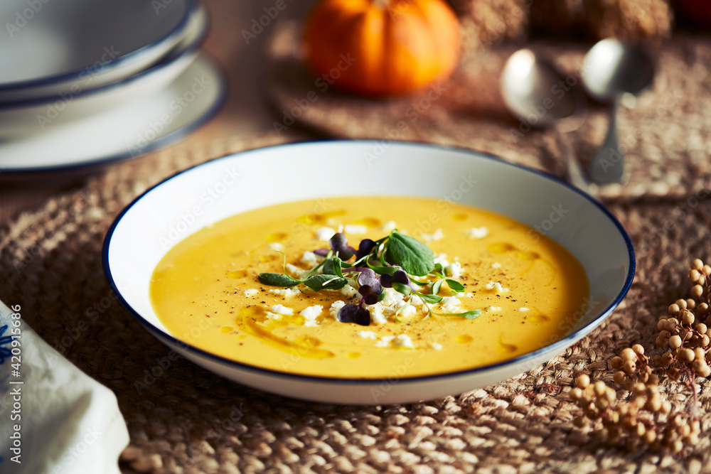 High angle close up of bowl of pumpkin soup with garnish on rustic place mat. High angle close up of bowl of pumpkin soup with garnish on rustic place mat.