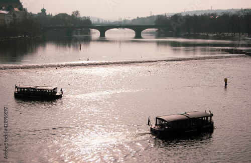 Embarcaciones sobre el río Vltava y al fondo uno de los muchos puentes que unen la ciudad de Praga photo