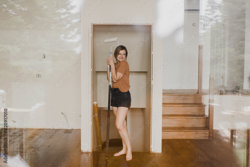 Woman holding paint roller stick in new home Woman holding paint roller stick in new home