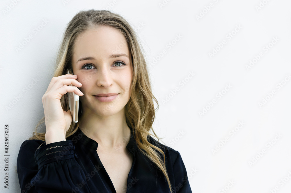 Young businesswoman talking on smartphone against white wall Young businesswoman talking on smartphone against white wall