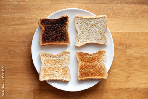 Four sliced bread on plate. Fresh, light toast, crispy toast and burnt