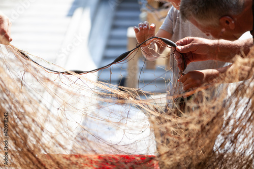 Fisherman and boy disentangling fishing net