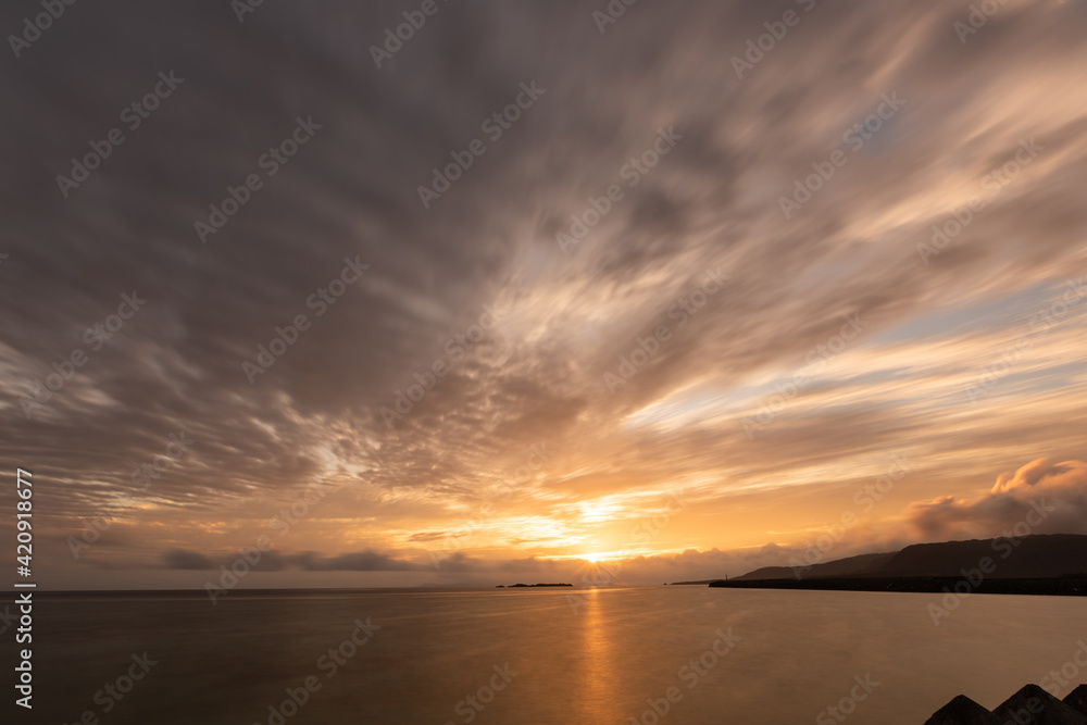 Beautiful sunrise seen from Uehara beach with an orange tone and beautiful clouds in the sky. Iriomote Island.