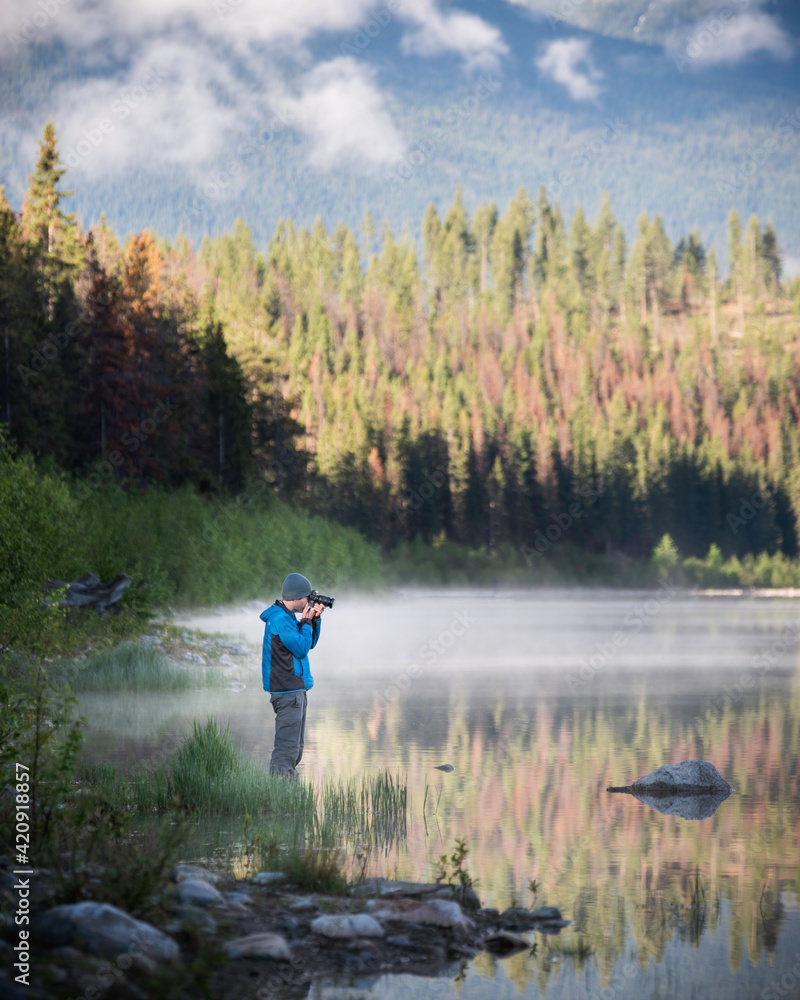 A photographer in a blue jacket lines up his shot along a bright and sunny morning in Jasper National Park.