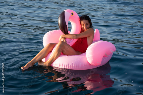 Woman on flamingo float on sea, Italy