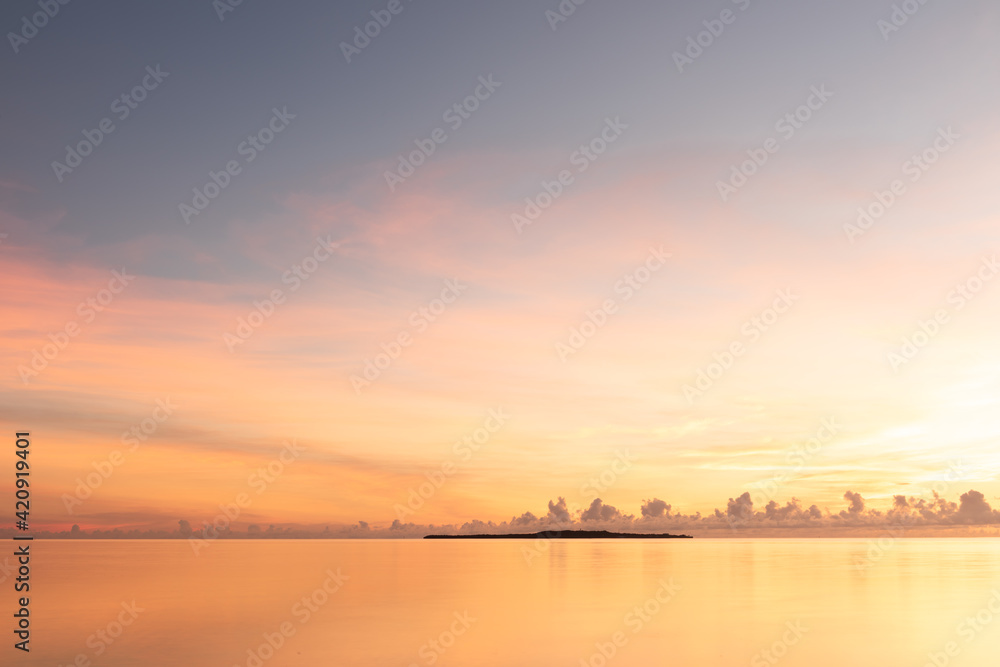 Gorgeous serene sunrise, smooth sea, colorful pastel tones sky, Hatoma island in silhouette in the background. Iriomote Island.