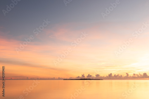 Gorgeous serene sunrise, smooth sea, colorful pastel tones sky, Hatoma island in silhouette in the background. Iriomote Island.
