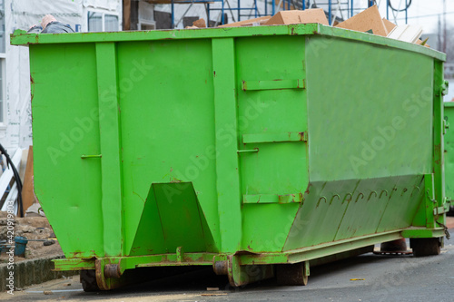 one big iron dumpster stands on the pavement full © Victor