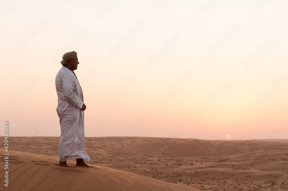 Omani man standing on sand dunes, Wahiba Sands desert, Oman Omani man standing on sand dunes, Wahiba Sands desert, Oman