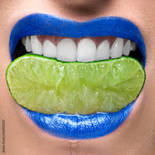 Blue lips biting on lime slice photo