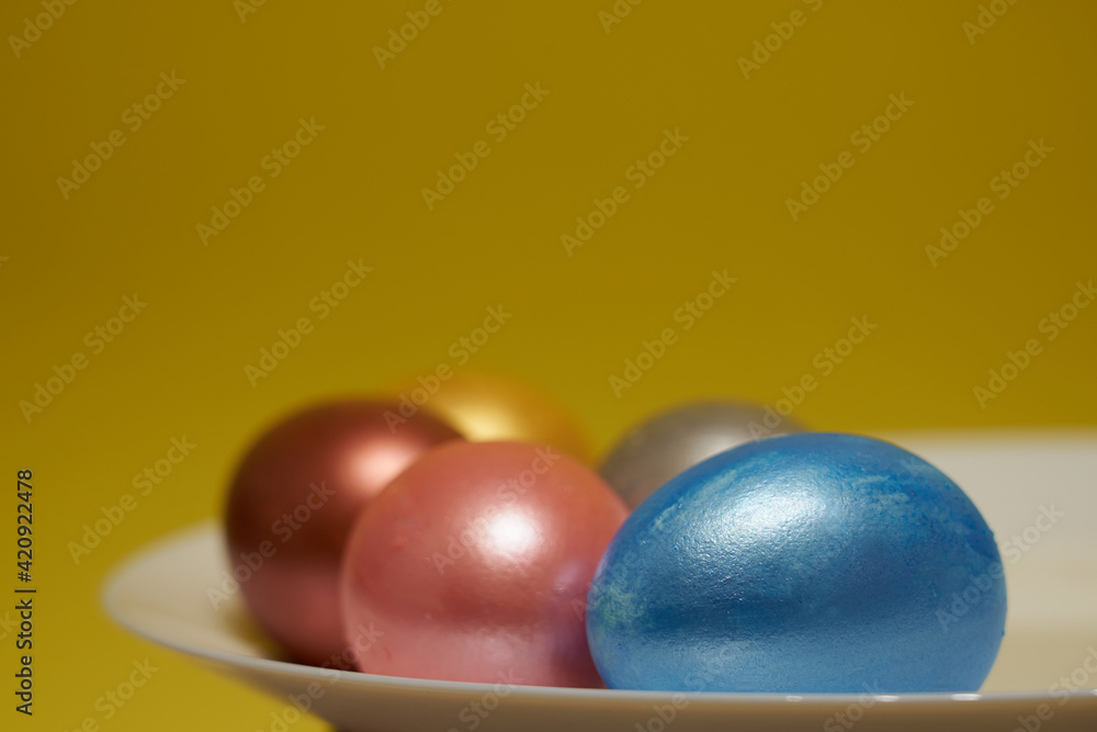 Painted eggs on a white plate with a yellow background. Painted eggs on a white plate with a yellow background.