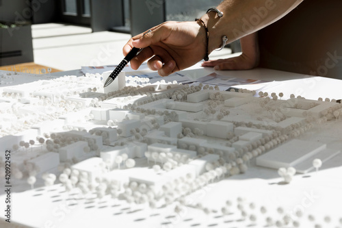 Close up of young architect pointing at architectural model. photo
