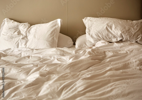 Unmade bed with crumpled duvet and pillows