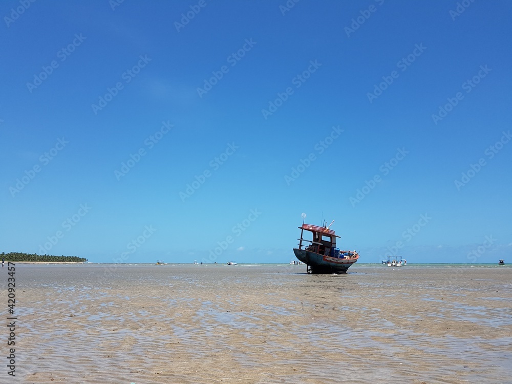 Barco ancorado na areia de praia durante a maré baixa