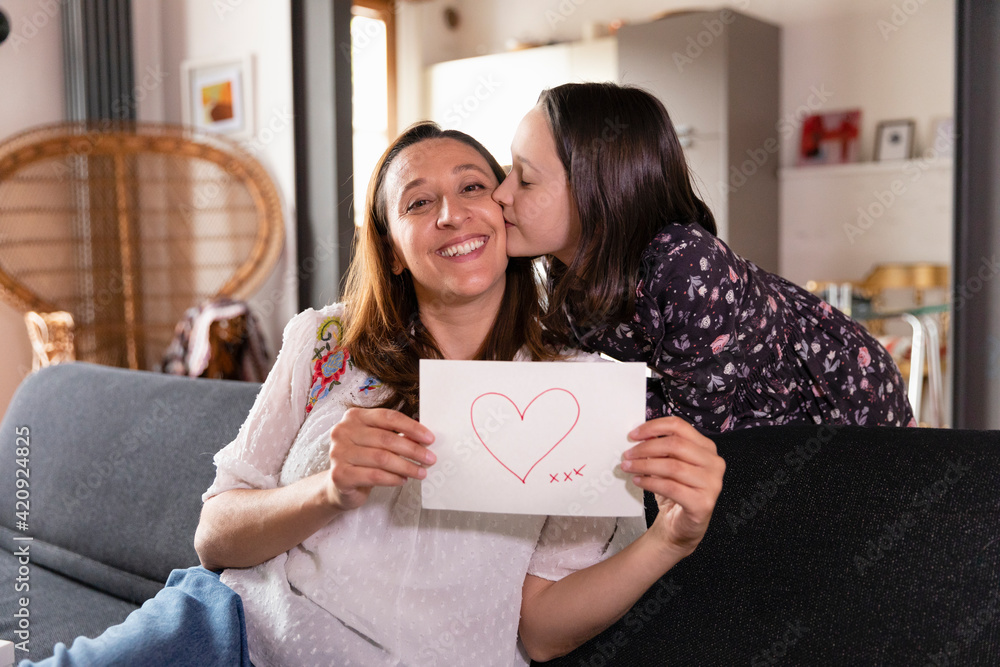Mother and daughter holding drawing with heart shape, online celebration during Coronavirus lockdown. Mother and daughter holding drawing with heart shape, online celebration during Coronavirus lockdown.