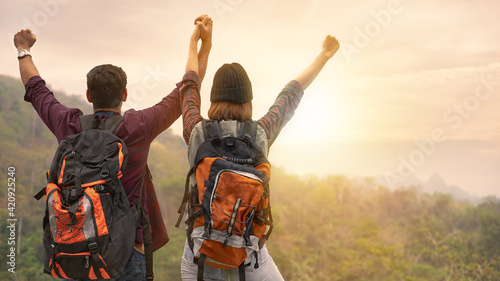 A tourist couple is excited while watching the sunrise on the mountain.