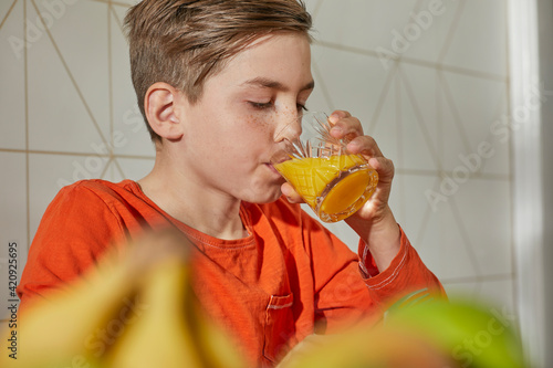Boy sitting at breakfast table, drinking orange juice.