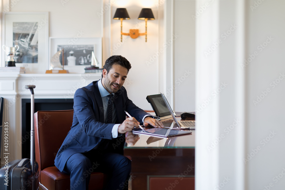 Businessman sitting at a table, writing on digital tablet. Businessman sitting at a table, writing on digital tablet.