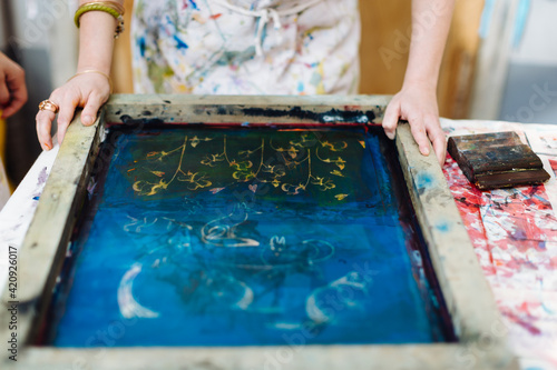 Woman doing silk screen print in creative studio, mid section, close-up