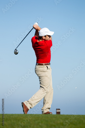 Male golfer teeing off.