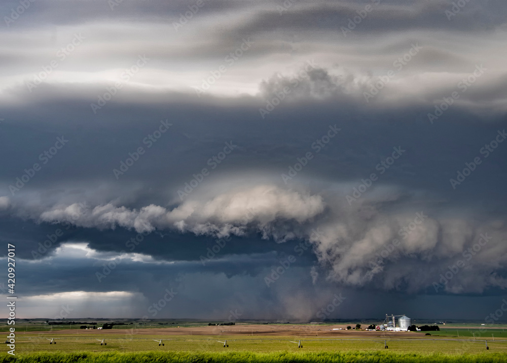 Dark and light wall clouds spin below a tornado super-cell kicking up dust into the updraft base. Dark and light wall clouds spin below a tornado super-cell kicking up dust into the updraft base.