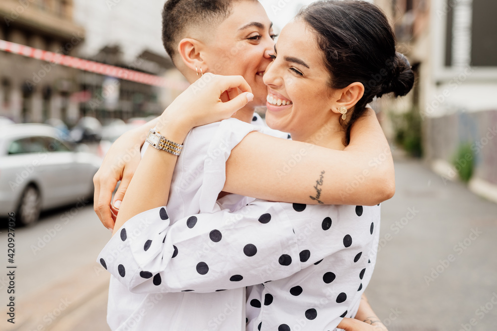 Portrait of young lesbian couple standing outdoors, hugging. Portrait of young lesbian couple standing outdoors, hugging.