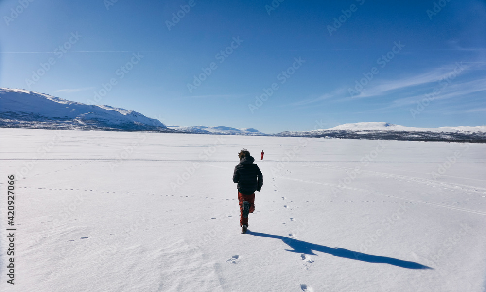 Rear view of two boys running across frozen lake in Vasterbottens Lan, Sweden. Rear view of two boys running across frozen lake in Vasterbottens Lan, Sweden.