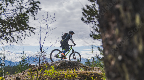 Woman mountain-biking in a forest in the Canadian mountains in British Columbia. photo