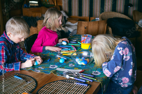 Boy and two girls sitting at a table in a log cabin, doing handicrafts, Vasterbottens Lan, Sweden. photo