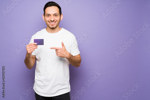 Hispanic man smiling while holding a credit card