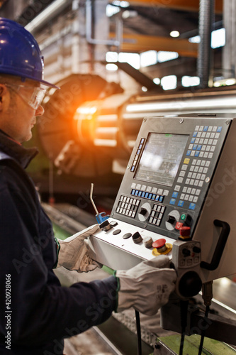 Man working in a steel factory, operating computerized machine. photo