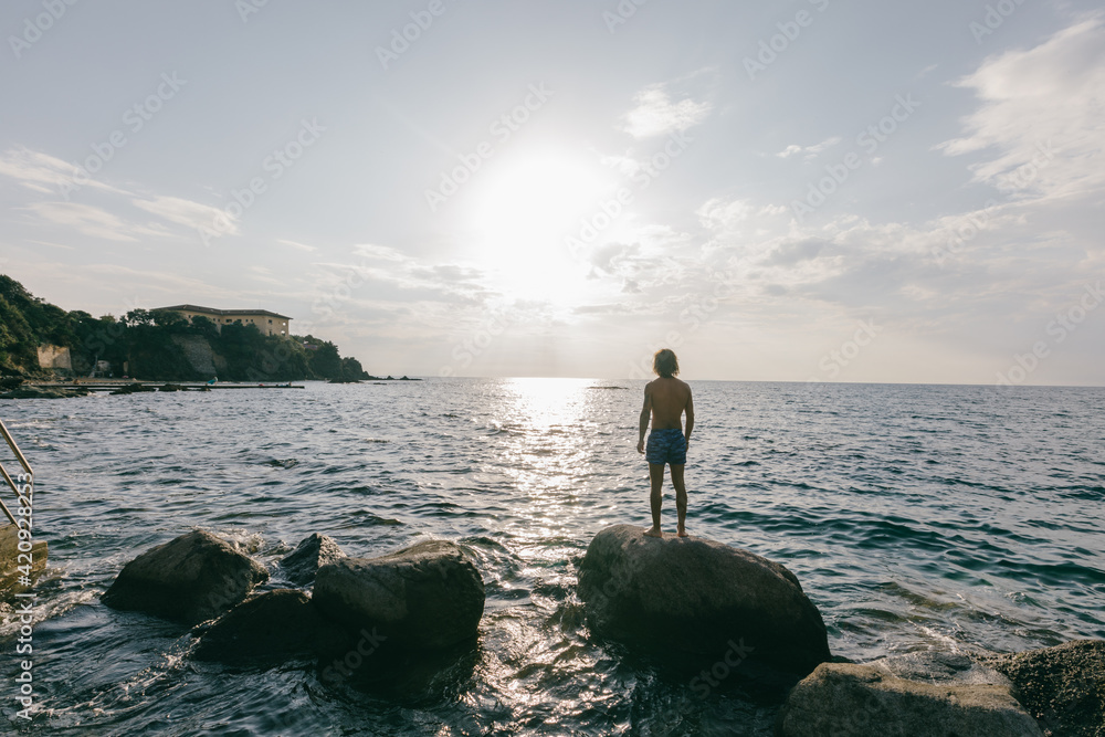 Man standing on rock in sea Man standing on rock in sea