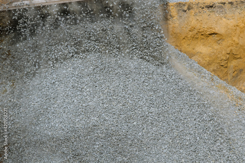 Yellow wheel unloading gravel at construction work equipment machinery for construction of foundation photo