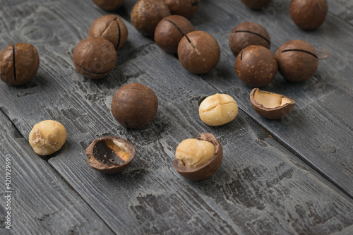 Whole and peeled macadamia nuts scattered on a wooden table.