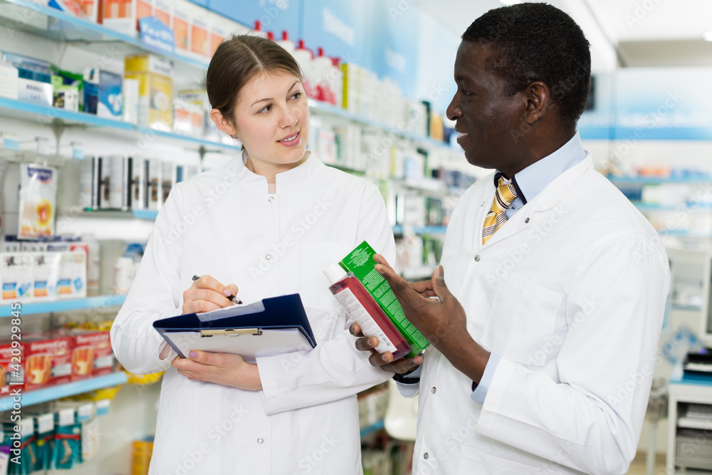male and female pharmacists working at drugstore, checking medicines inventory.