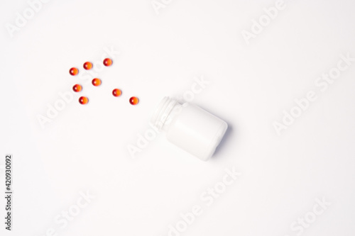 A jar with multi-colored pills arranged in a certain order on a Light background Copy Space top view