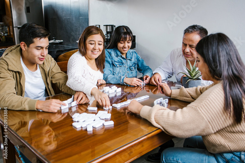 Latin family, mother, father, son and daughter playing domino game  at home in Mexico © Marcos
