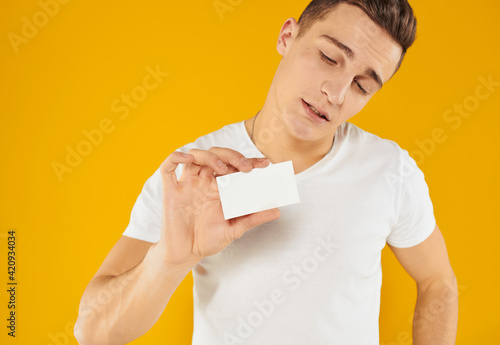 young man on a yellow background holds a credit card in his hand and Copy Space