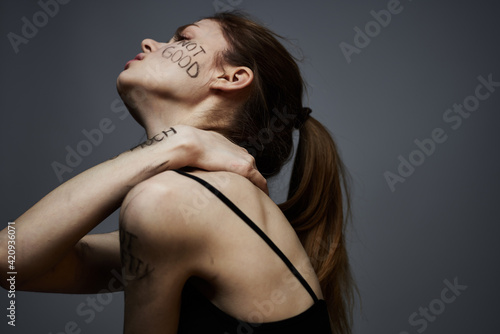 Woman in a black T-shirt lettering on the body upset discontent dark background