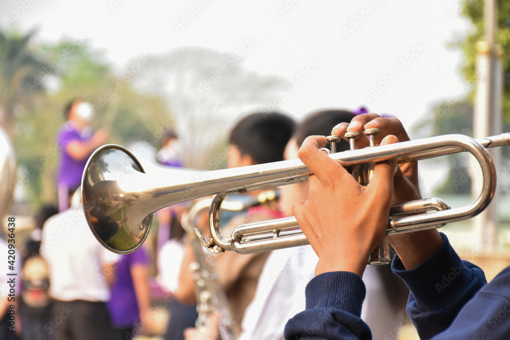 Fototapeta premium Trumpet instrument holding in hands of Asian student who playing it at a ceremony to honor the national flag in the morning. Soft and selective focus on trumpet.