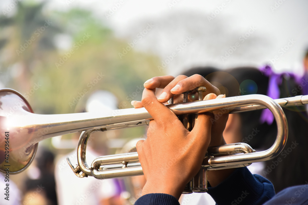 Obraz premium Trumpet instrument holding in hands of Asian student who playing it at a ceremony to honor the national flag in the morning. Soft and selective focus on trumpet.