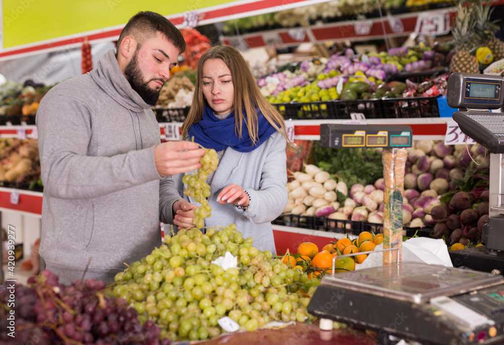 Young couple picks grapes at the grocery store. High quality photo