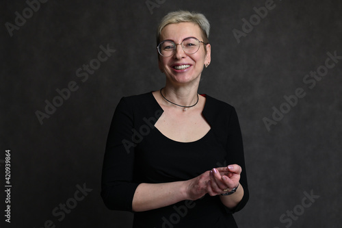 Photo of a blonde caucasian woman in glasses with a short haircut on a black background