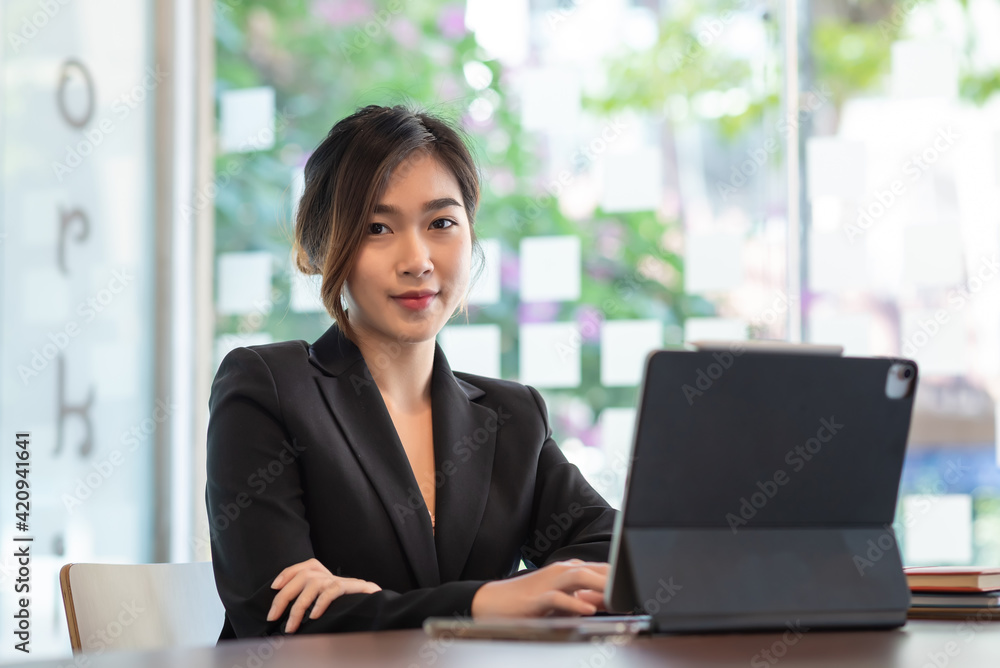 Asian beautiful businesswoman sitting at the office with a tablet Looking at the camera. Asian beautiful businesswoman sitting at the office with a tablet Looking at the camera.