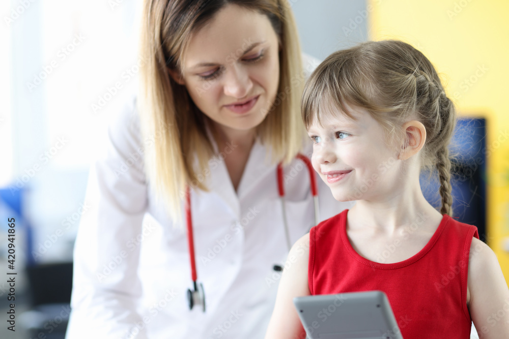 Little girl holding mobile phone in doctors office Little girl holding mobile phone in doctors office