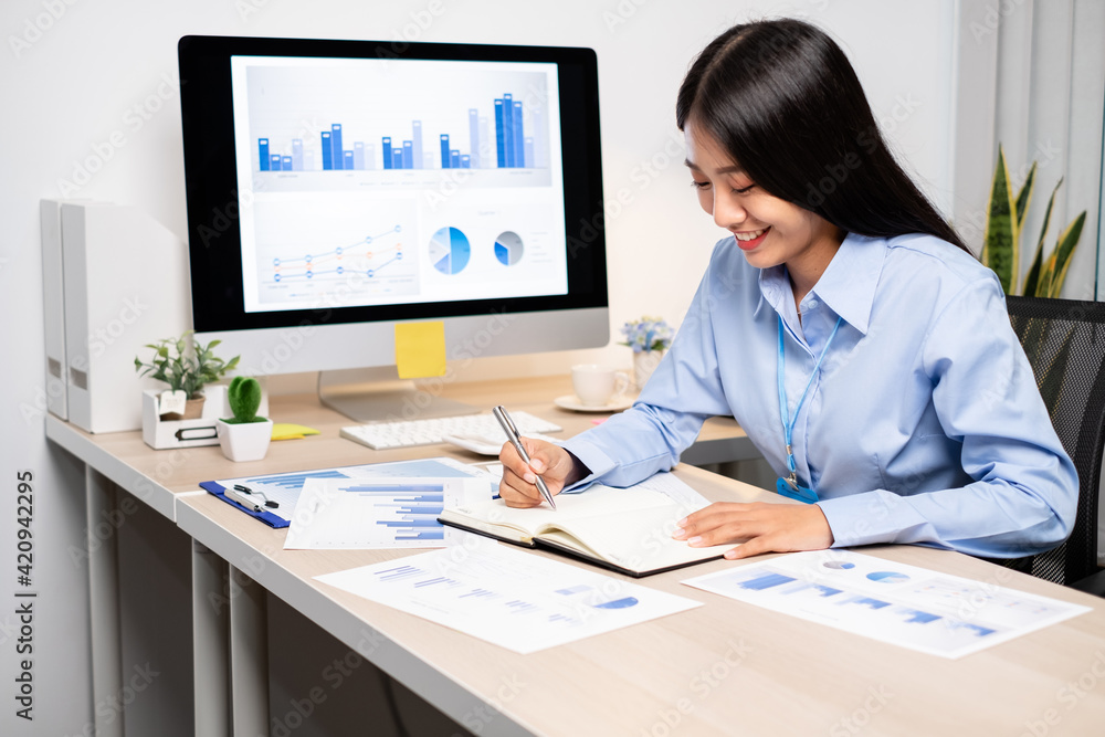 Asian women sit at their desks and calculate financial graphs showing results about their investments, plan a successful business growth process Asian women sit at their desks and calculate financial graphs showing results about their investments, plan a successful business growth process