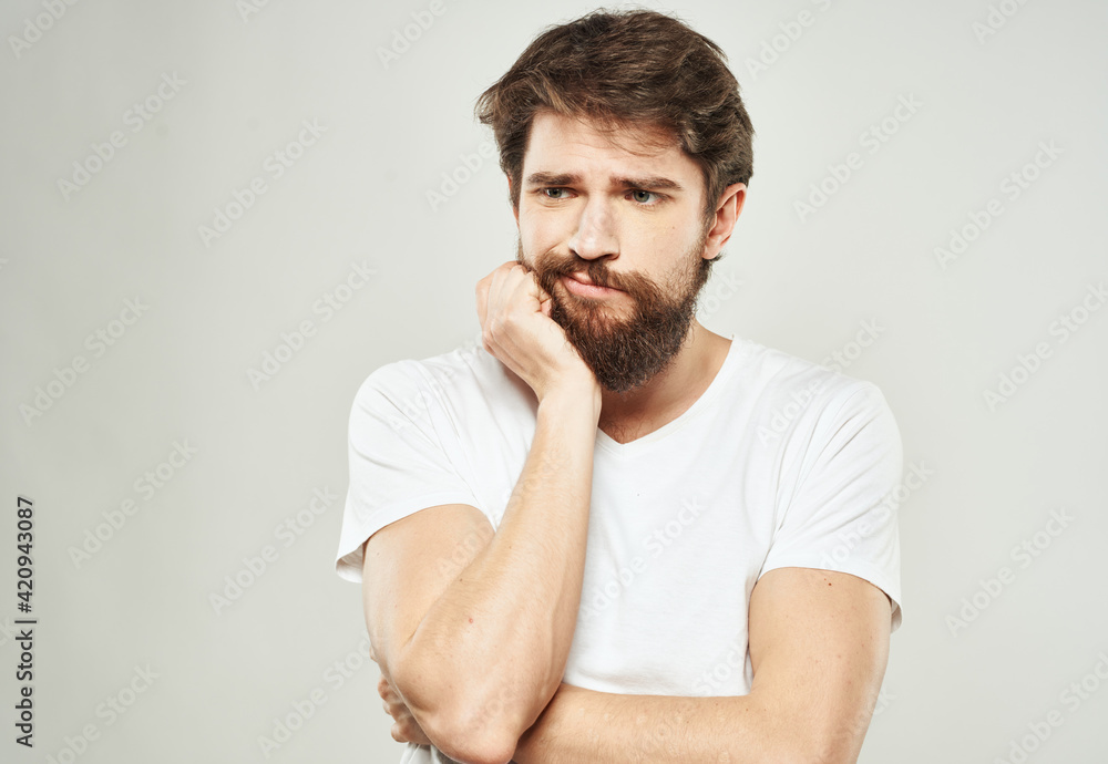 a man with a puzzled look looks to the side on a light background and a thick beard a man with a puzzled look looks to the side on a light background and a thick beard